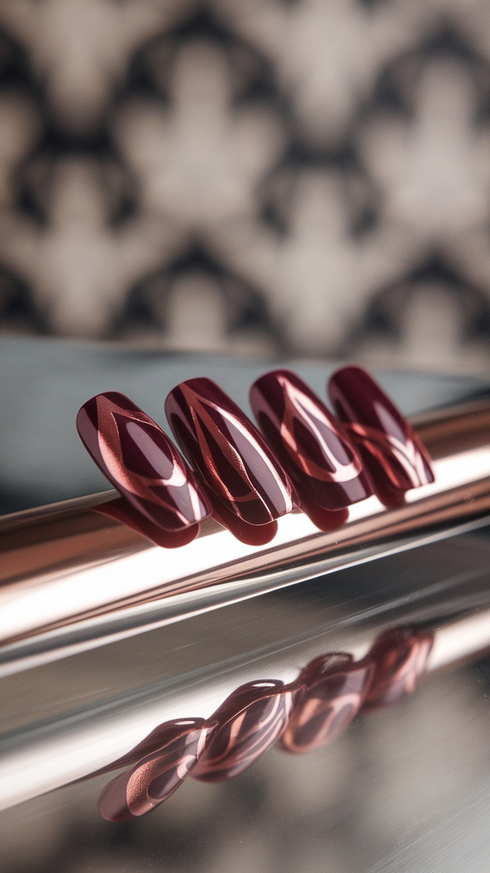 Nail design featuring burgundy and copper metallic colors with a modern shape.