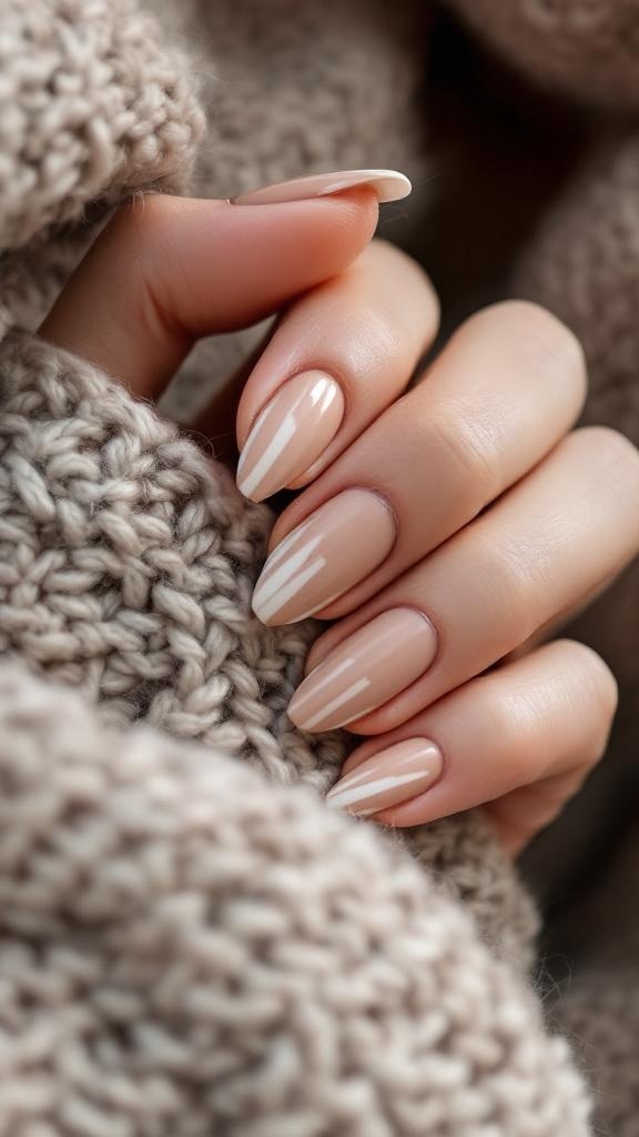 Close-up of warm taupe nails with white stripes, resting on a knitted sweater