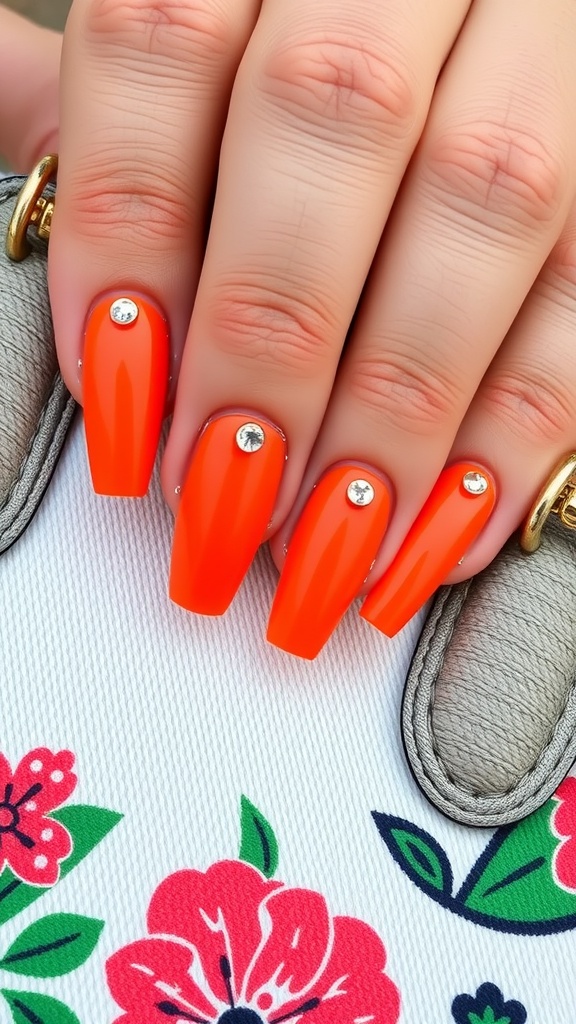 Close-up of bold orange nails with rhinestones on a floral background