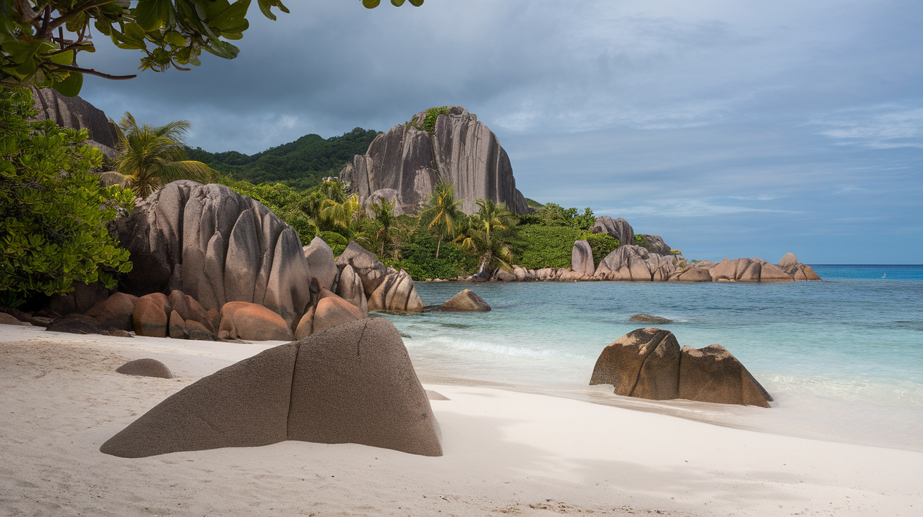 Granite boulders on a beach in Seychelles with clear blue water and lush greenery.