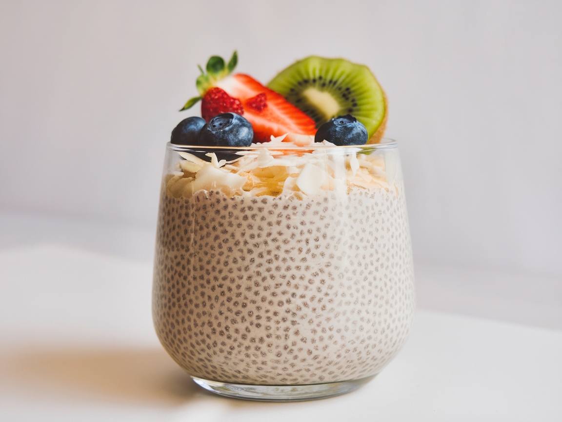 Chia seed pudding topped with fresh fruits and coconut flakes, with a pineapple in the background